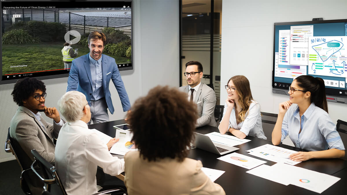 Business meeting in a conference room with participants using SMART NX and QX series displays, showcasing interactive technology.