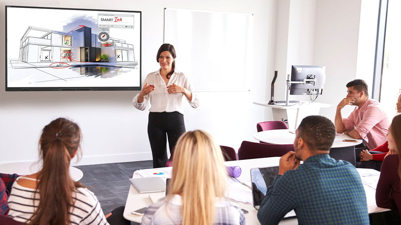 Teacher presenting architectural concepts on an interactive display in a modern classroom.