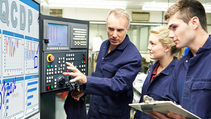 Team of engineers analyzing production data on a SMART Board in manufacturing facility