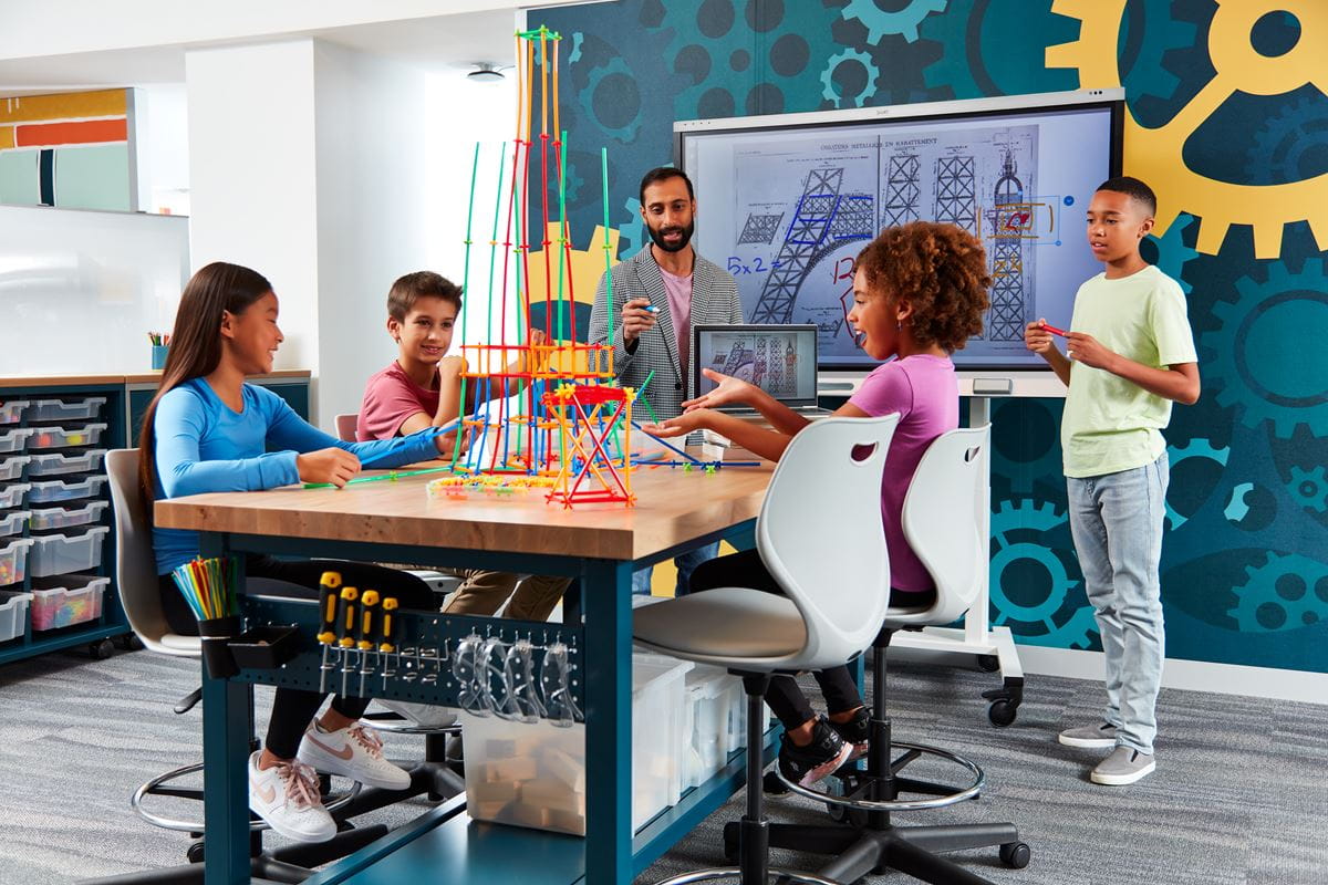 Students engaging in a creative STEM project with a SMART board in the background, showcasing interactive learning.